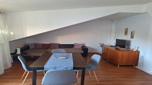 A modern living space with a dining table, sofa, and TV stand. - Apartments Ivan (Tisno)
