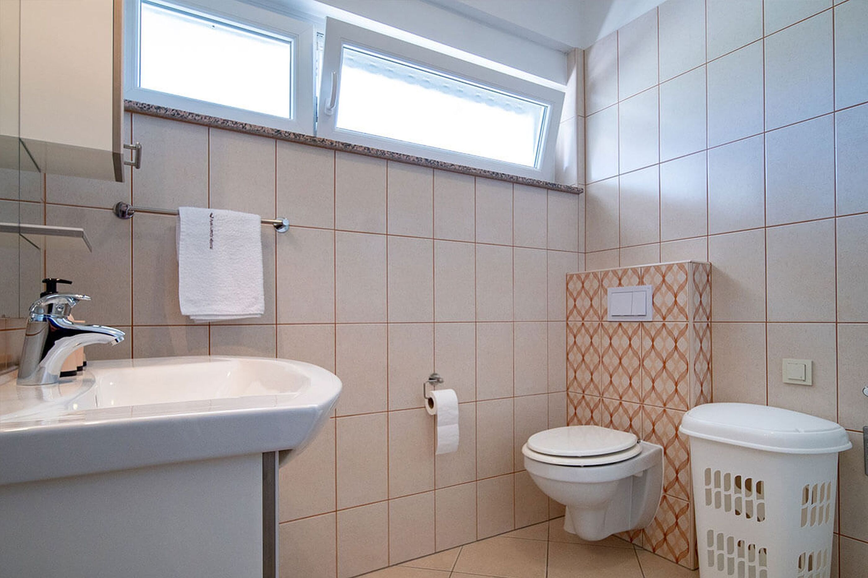 Une salle de bain équipée d’un lavabo, de toilettes et d’un panier à linge.