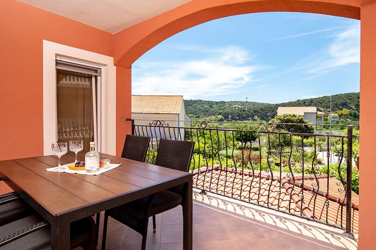 Ein Balkon mit Tisch, Stühlen und Blick auf eine grüne Landschaft.