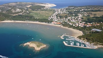 Vista aérea de una zona costera con playa, barcos y puerto deportivo.