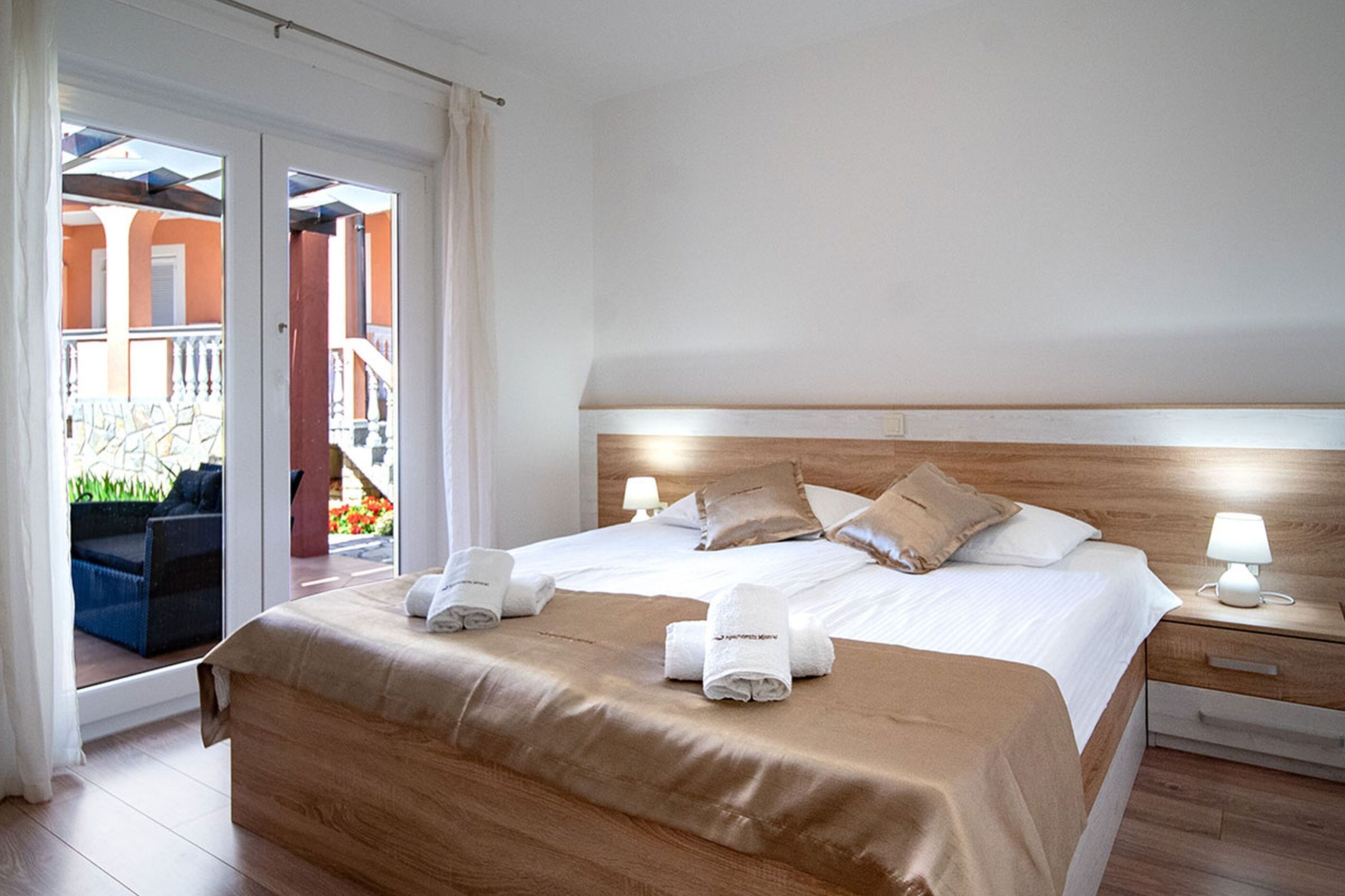 Una habitación de hotel con cama, mesita de noche, ventana con cortinas y vista a un área exterior.