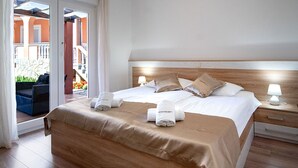 Una habitación de hotel con cama, mesita de noche, ventana con cortinas y vista a un área exterior.
