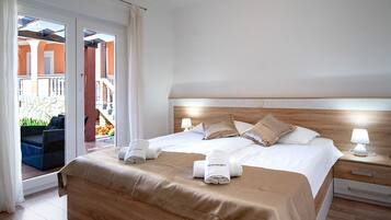 Una habitación de hotel con cama, mesita de noche, ventana con cortinas y vista a un área exterior.