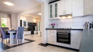 Una cocina moderna con armarios blancos, un comedor con mesa y sillas, y un horno visible.