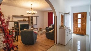 A living room with a fireplace, a dining area, and a kitchen with wooden cabinets. - House Relax Residence (Liznjan)