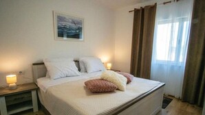 A bedroom with a bed, two bedside tables, a night lamp, a painting, and a window with curtains. - House Relax Residence (Liznjan)