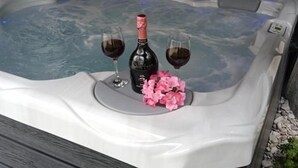 A hot tub with a bottle of wine and two glasses, surrounded by pink flowers. - House Relax Residence (Liznjan)
