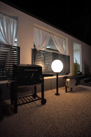 A patio area with a grill, a round light, and a potted plant. - Mobile Home Aura With Jacuzzi (Vodice)