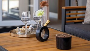 Interior moderno com mesa de madeira, dois copos, uma tigela de frutos secos, um vaso decorativo e uma planta.