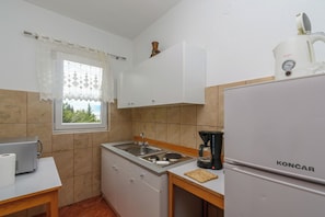 Eine kleine Küche mit Spüle, Kaffeemaschine, Kühlschrank und einem Fenster mit Blick.