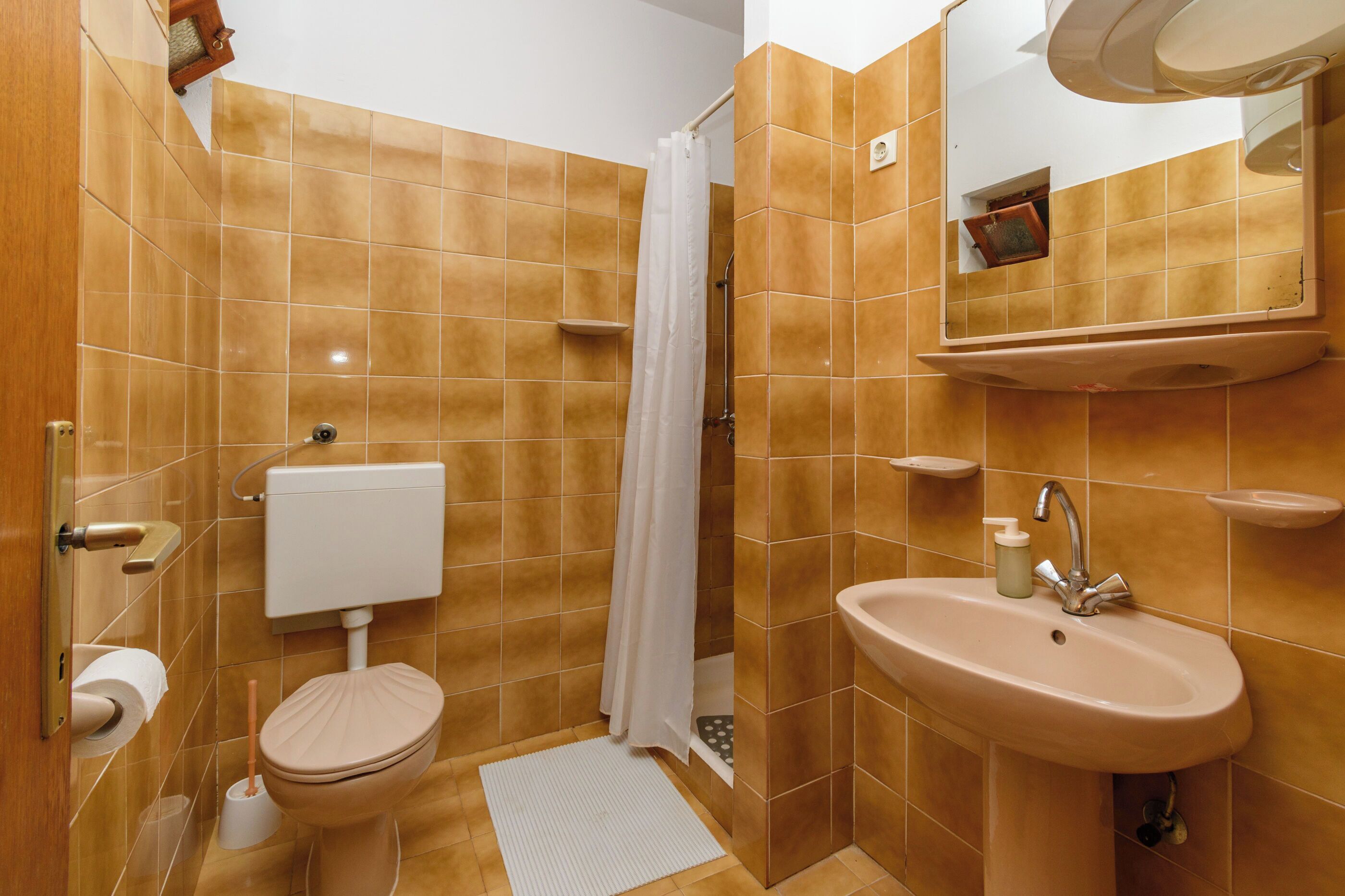 Un baño con inodoro, lavamanos, cortina de ducha y paredes de azulejos.
