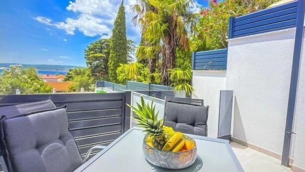 A balcony with a table, chairs, and a bowl of fruit. - Apartments Sladana (Crikvenica)
