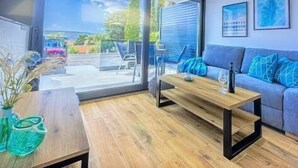A modern living room with a wooden coffee table, a blue sofa, and a grey sofa. - Apartments Sladana (Crikvenica)