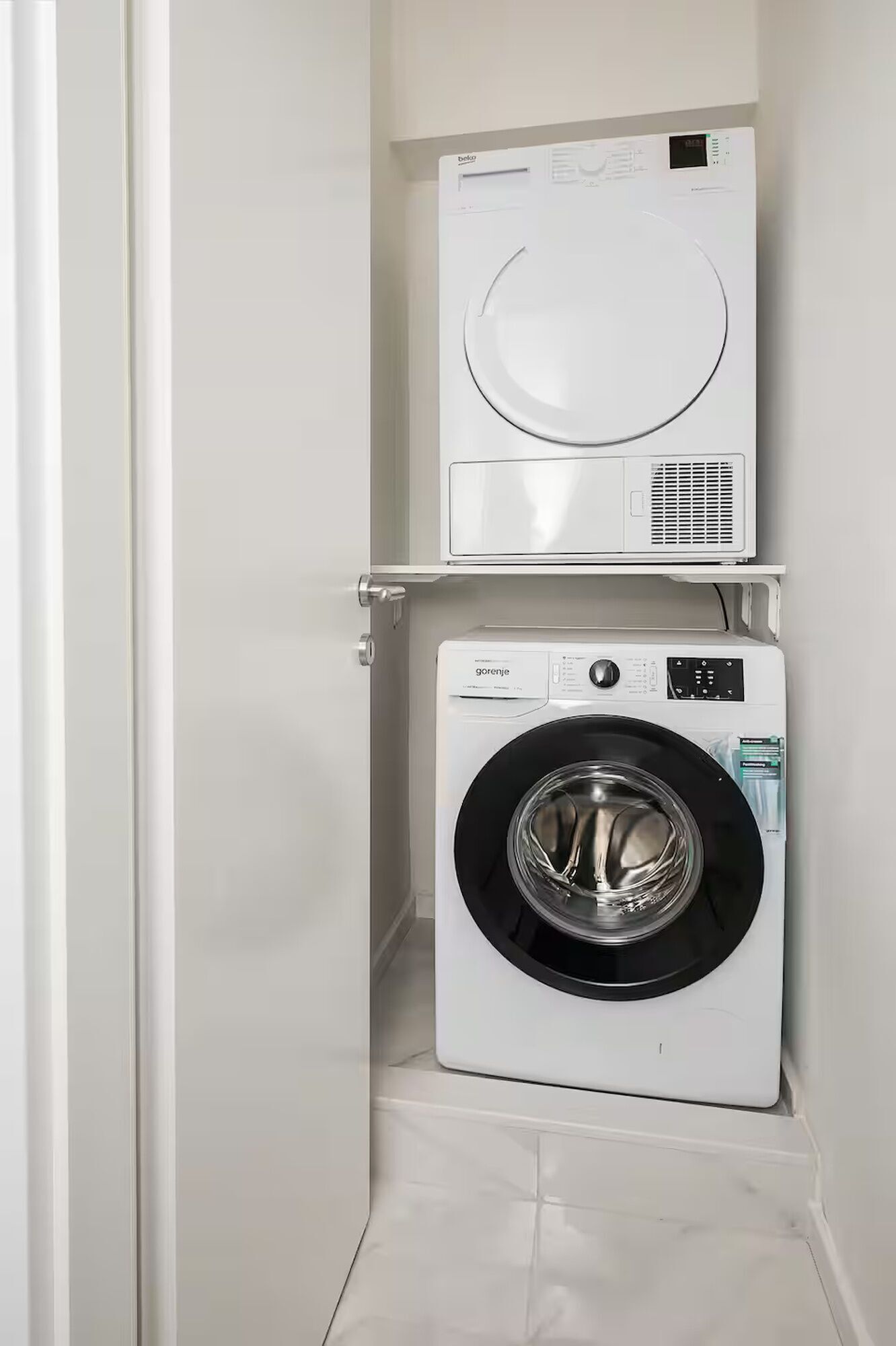 A compact laundry room with a top-loading washer and a front-loading dryer.