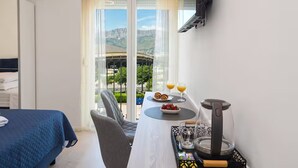 Ein Hotelzimmer mit Bett, Frühstückstisch, einer Kaffeemaschine und einem an der Wand montierten Fernseher.