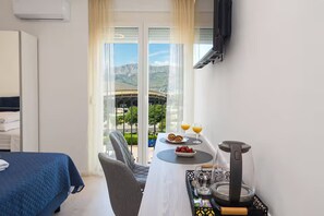 A hotel room with a bed, a dining table with breakfast, a coffee maker, and a TV mounted on the wall. - Apartment Tatjana (Split)