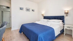 Ein Schlafzimmer mit Bett, Nachttischen, einem Sessel und Wandleuchten.