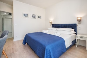 A bedroom with a bed, bedside tables, a chair, and wall-mounted lights. - Apartment Tatjana (Split)