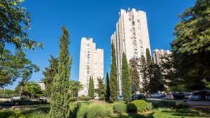 Ein Wohngebiet mit hohen Wohnblocks, grünen Bäumen und geparkten Autos.