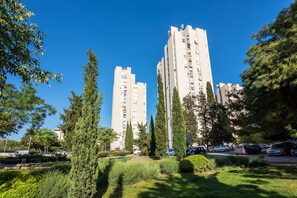 A residential area with tall apartment buildings, green trees, and parked cars. - Apartment Tatjana (Split)