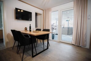 A dining area with a table, chairs, a TV, and a sliding glass door to a balcony. - Mobile Home Aria With Jacuzzi (Vodice)