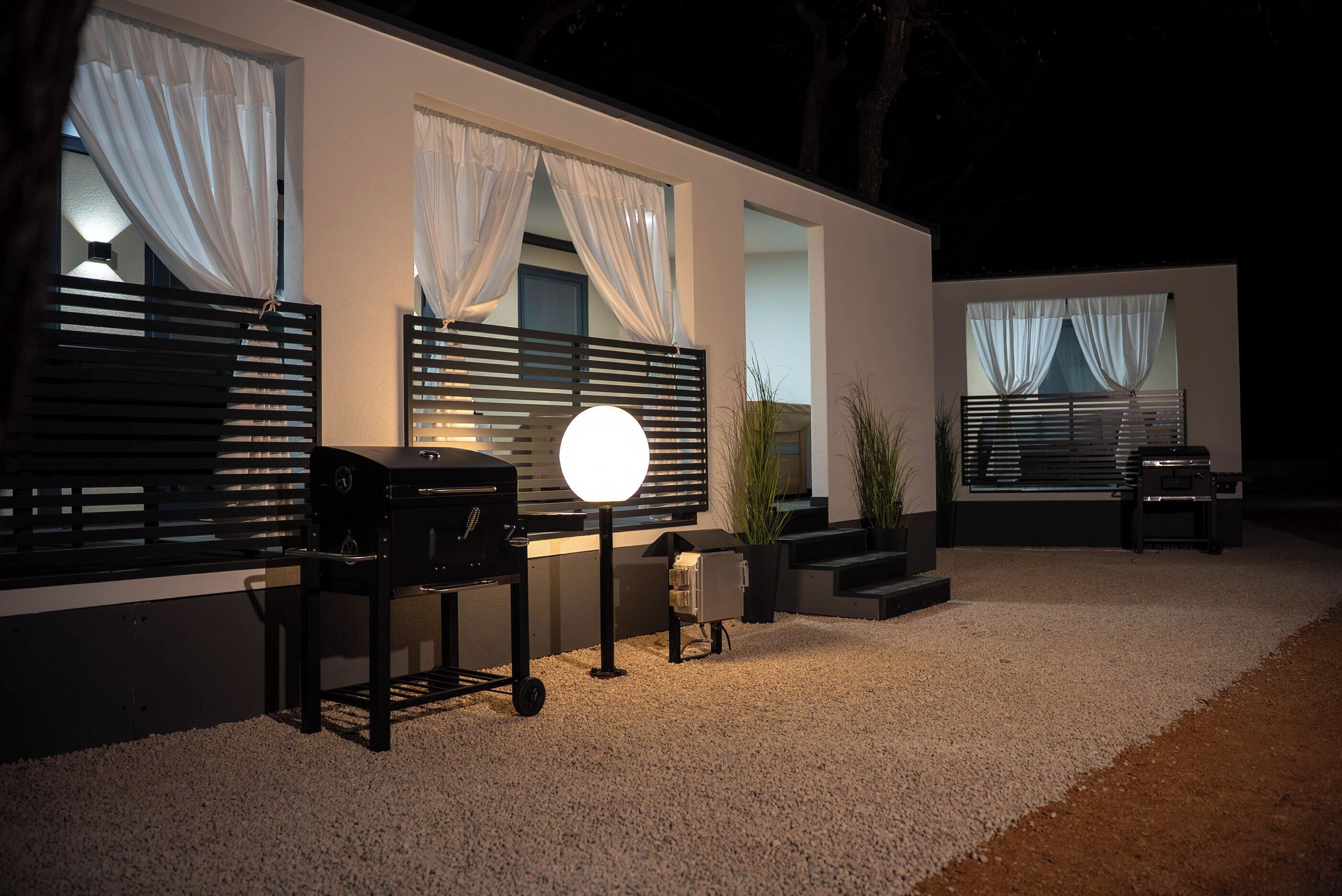Un patio al aire libre moderno con una parrilla, una mesa redonda y un banco para sentarse.