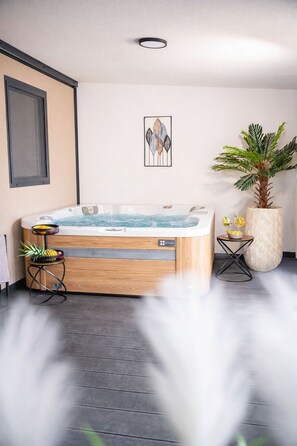 Ein modernes Badezimmer mit freitragender Badewanne, einer Topfpflanze und einem gerahmten Kunstwerk an der Wand.