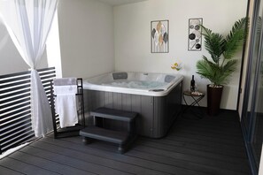 A spa area with a hot tub, a towel rack, a small table with a bottle and glass, and a potted plant. - Mobile Home Maris With Jacuzzi (Vodice)