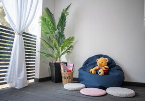 A room with a blue bean bag chair, a teddy bear, a potted plant, a wicker basket labeled 'TOYS,' and a white curtain. - Mobile Home Maris With Jacuzzi (Vodice)