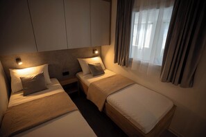 A hotel room with two single beds, a nightstand, a wall-mounted light, and a window with curtains. - Mobile Home Maris With Jacuzzi (Vodice)