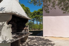 An outdoor grill area with a chimney, a concrete bench, and a white wall. - Apartment Buska Near Sea (Vir)