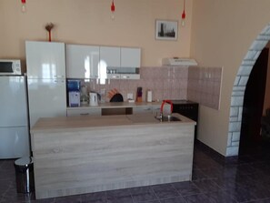A modern kitchen with white cabinets, a built-in island, a sink, and a microwave. - Apartment Buska (Vir)