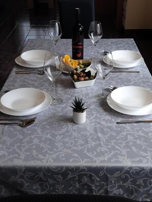 A table set for dining with plates, cutlery, and a bottle of wine. - Apartment Buska (Vir)