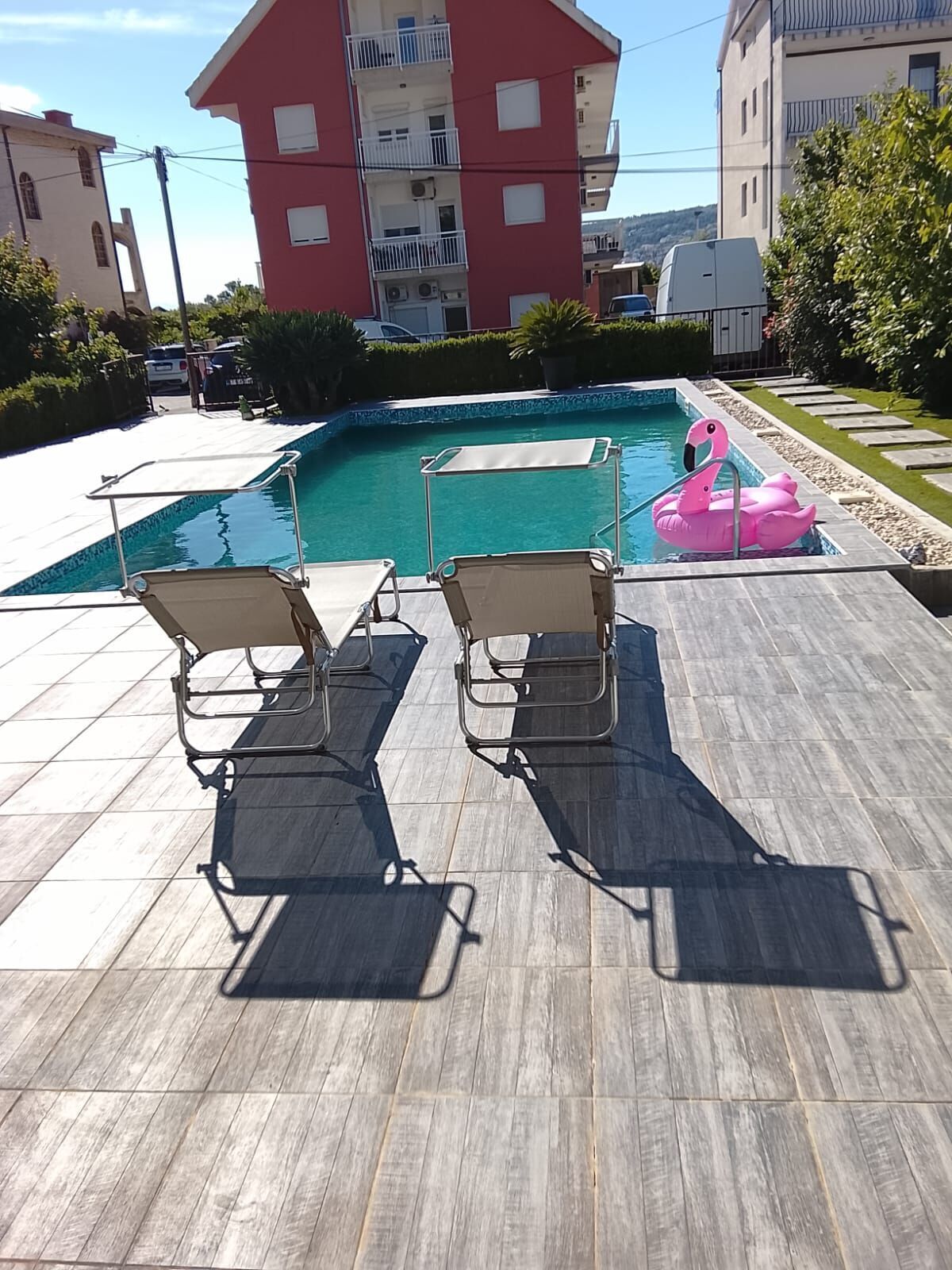 A swimming pool with lounge chairs and a pink flamingo float.