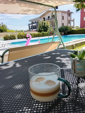 Ein Tisch mit einem Glas mit schichtweise Getränk, einem rosa Flamingo-Schwimmreifen und einer Topfpflanze.