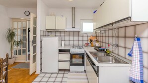 Une cuisine de taille réduite équipée d’un réfrigérateur, d’un four, d’une cuisinière, d’un évier et d’une fenêtre située au-dessus du plan de travail.