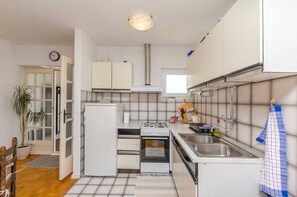 Eine kompakte Küche mit Kühlschrank, Backofen, Herd, Spüle und einem Fenster über der Arbeitsfläche.