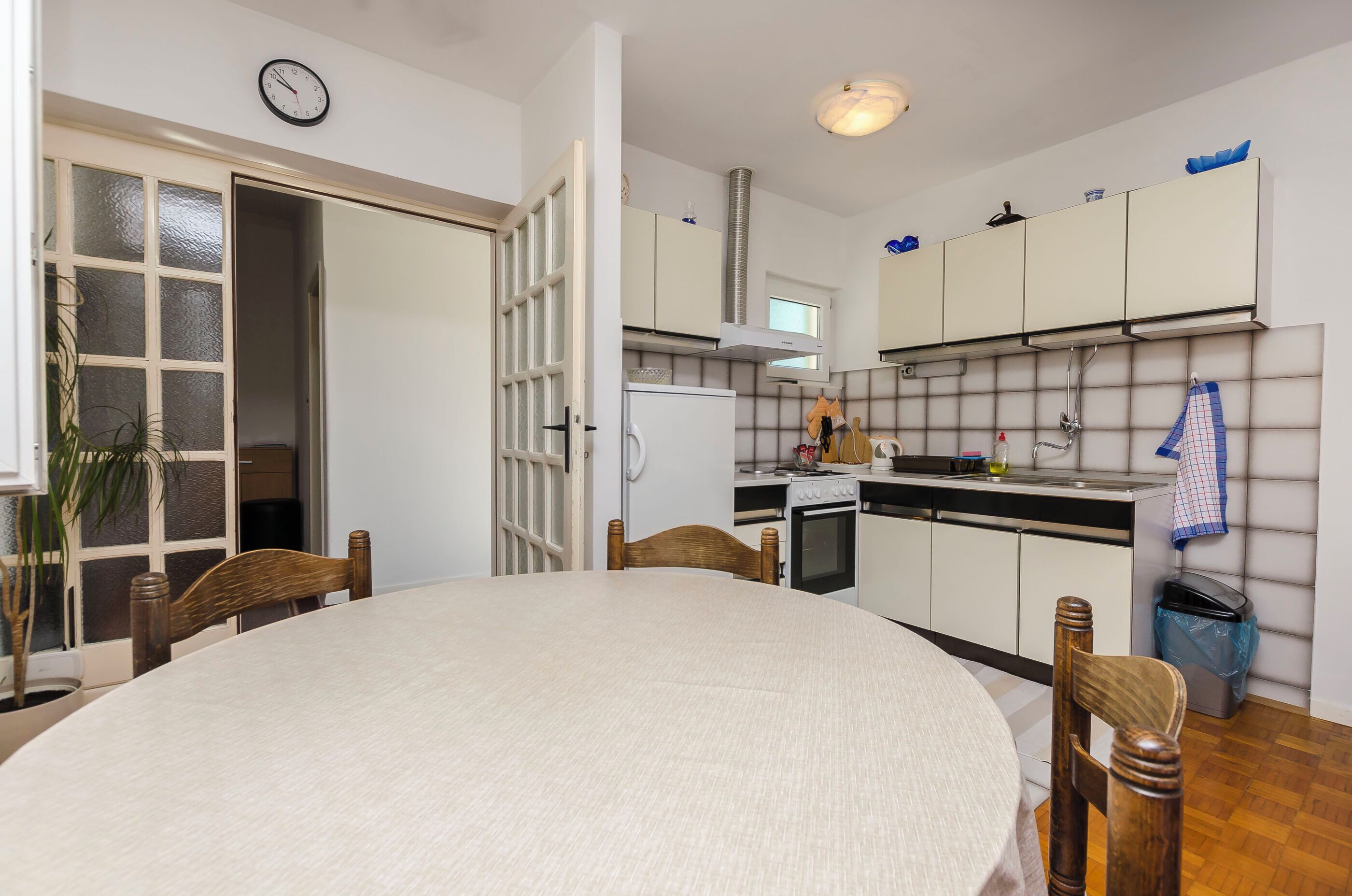 A kitchen with white cabinets, a stove, and a sink. There is a dining table with chairs.