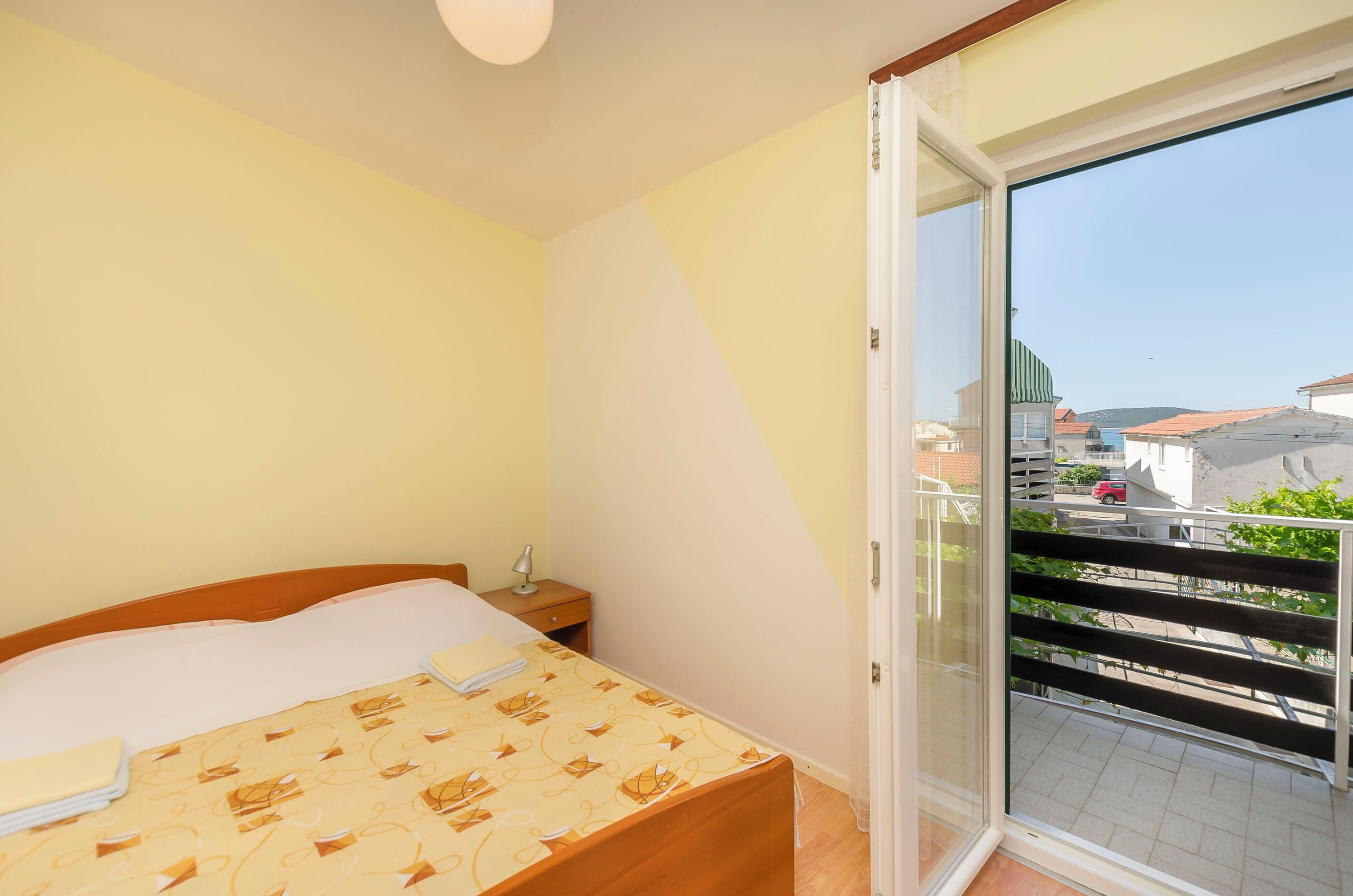 Une chambre à coucher avec un lit, une table de chevet et une vue sur l’extérieur grâce à une porte-fenêtre coulissante.