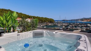 Een bubbelbad met uitzicht op een jachthaven en een heuvel op de achtergrond.