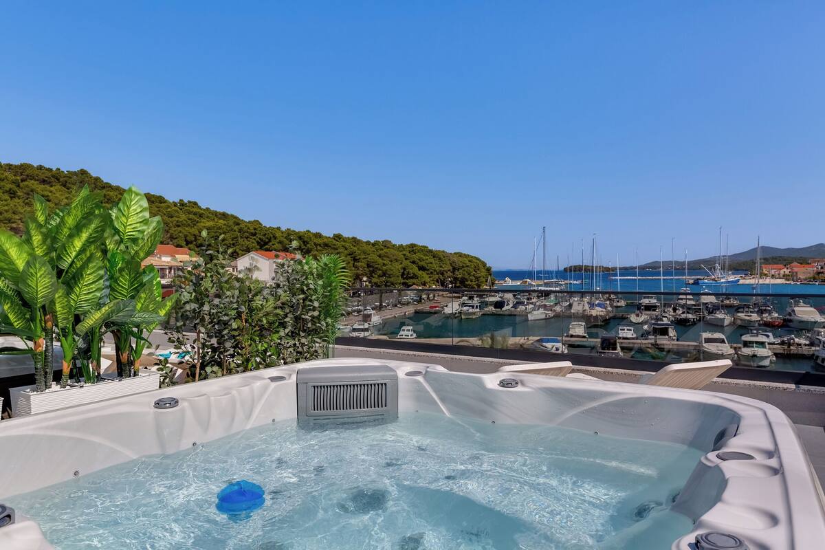 Ein Whirlpool mit Blick auf einen Yachthafen und eine Hügelkulisse im Hintergrund.