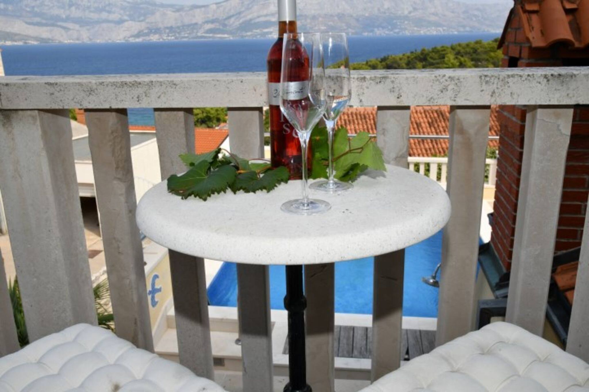 A balcony with a table, two wine glasses, and a bottle of wine.