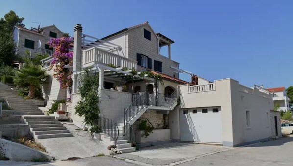 A two-story building with a balcony, a staircase leading to the upper floor, and a garage. - House Postira Horizon (Postira)