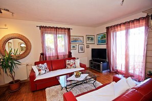 A living room with a red sofa, a coffee table, a TV, and a large mirror. - House Postira Horizon (Postira)