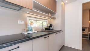 Una cocina moderna con encimera negra, armarios blancos, una ventana y una cafetera.