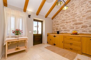 Eine Küche mit einem Holzkabinett, einem kleinen Tisch mit Blumen in einer Vase und einer Steinwand.
