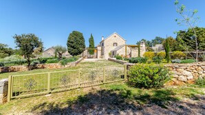 A stone house with a garden, a stone wall, and a metal fence. - House Bilusic (Jelsa)