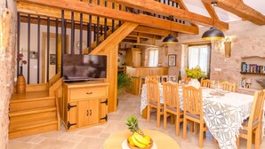 A wooden staircase leading to a loft bedroom, a dining area with a table set for four, and a kitchen area. - House Bilusic (Jelsa)