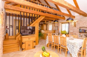 A wooden staircase leading to a loft bedroom, a dining area with a table set for four, and a kitchen area. - House Bilusic (Jelsa)