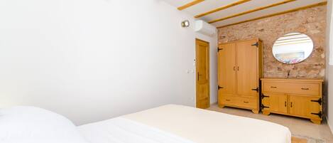 A bedroom with a bed, wooden wardrobe, and a round mirror.